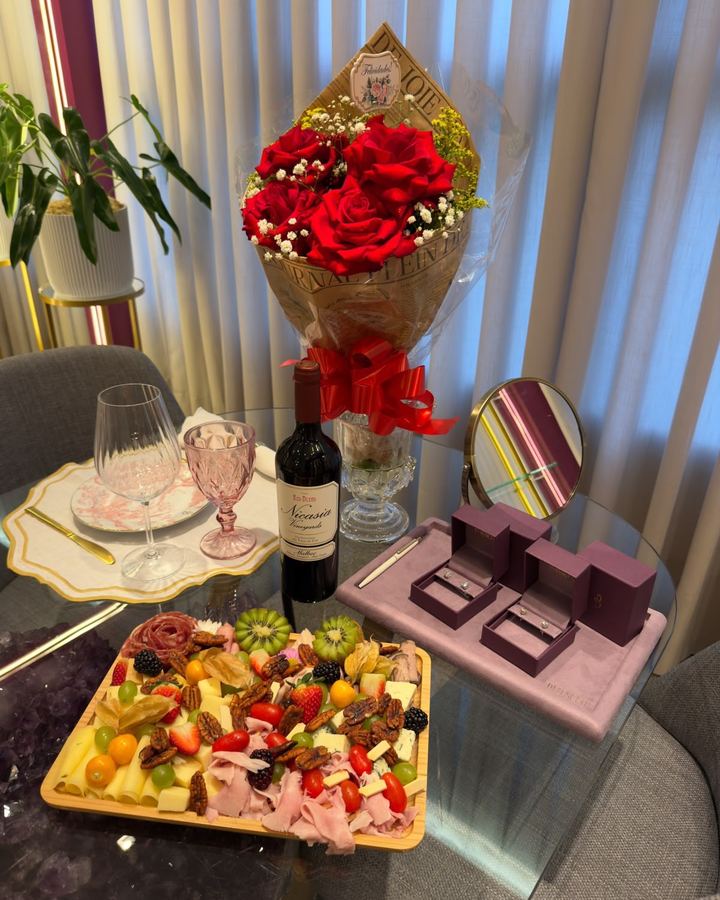 Mesa preparada no showroom com flores, tábua de frios e anéis apresentados em estojos da Di Benetti